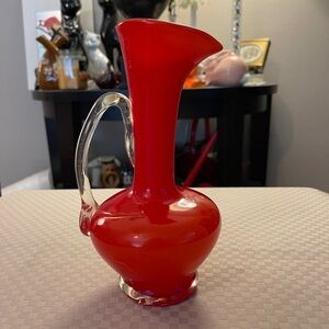 Vintage hand blown red cased glass pitcher with clear applies handle, 8” high.